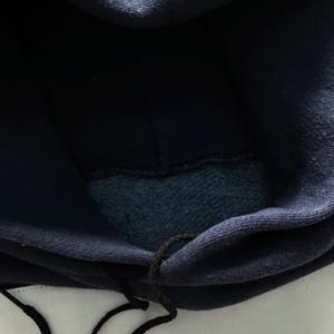 May include: A navy blue hooded sweatshirt with a dark blue fleece lining. The hood is pulled up and the drawstring is visible.