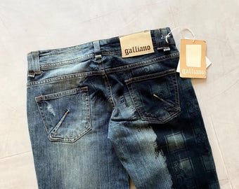 May include: Blue denim jeans with distressed details and a faded wash. The back features two pockets and a leather patch with the brand name "galliano". A hang tag with the brand name is attached. The jeans have a unique pattern on the right leg.