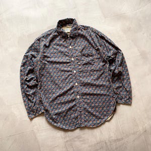 May include: A long-sleeved button-down shirt with a blue floral pattern. The shirt has a chest pocket and a classic collar. The fabric appears to be a soft, woven material.