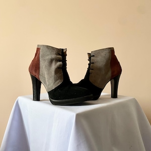 Peut inclure: Une paire de bottines avec un design color block. Les bottines présentent une base noire, des panneaux en daim gris et marron et un talon haut noir. Les bottines sont lacées sur le devant et reposent sur une semelle plateforme.