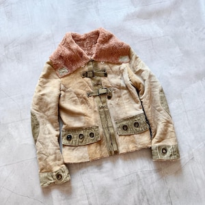 May include: A tan suede jacket with a faux fur collar and lining. The jacket features olive green accents on the pockets, elbows, and cuffs. It has a series of buckles down the front and decorative buttons on the pockets and cuffs.