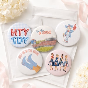 May include: Five circular pinback buttons featuring various designs: one with blue gingham and red and blue text reading HTY TDY, one with a stadium illustration and text See You In Oxford, one with a cartoon mascot, one with blue cowboy boots and text Meet Me In The Grove, and one with four illustrated figures holding signs spelling REBS.