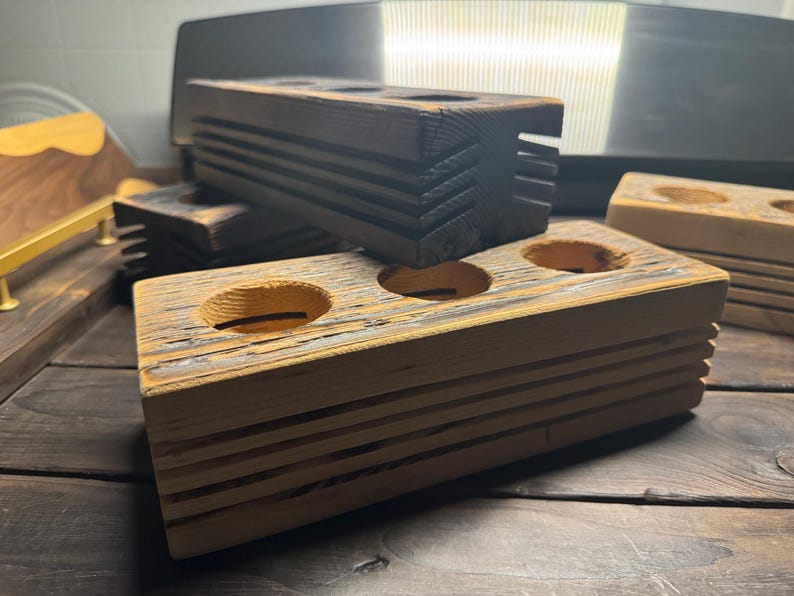 May include: A wooden stand with three circular cutouts, perfect for holding small items like essential oils or candles. The stand is made of reclaimed wood and has a rustic, weathered look.