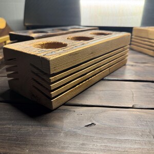 May include: A wooden organizer with three round holes, perfect for storing small items like pens, pencils, or brushes. The organizer has a rustic, reclaimed wood look and is made of natural wood.