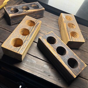 May include: Four wooden blocks with three circular cutouts in each. The blocks are stacked on top of each other and have a rustic, distressed look. The wood is a light brown color with dark brown streaks.