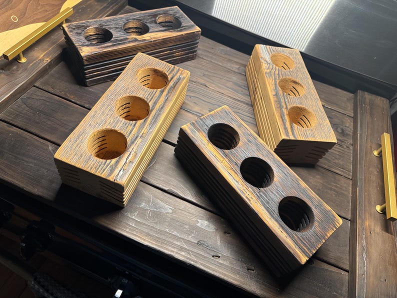 May include: Four wooden blocks with three circular cutouts in each. The blocks are stacked on top of each other and have a rustic, distressed look. The wood is a light brown color with dark brown streaks.