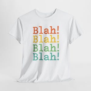 May include: White t-shirt with the text "Blah!" repeated four times in a rainbow color pattern.