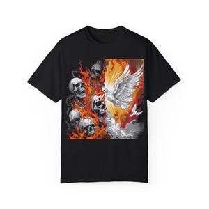 Pode incluir: Camiseta preta com uma estampa gráfica de uma pomba branca voando sobre uma cena de fogo com caveiras e correntes. A pomba está cercada por um brilho laranja e amarelo brilhante.