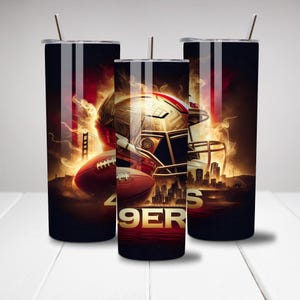 May include: Three black stainless steel tumblers with a gold football helmet and a football in front of a fiery background. The text "49ERS" is visible on the tumbler in the center.