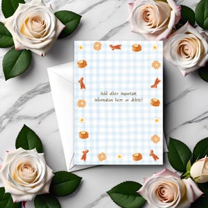 May include: A white envelope with a blue and white checkered card featuring illustrations of breakfast foods like pancakes, bacon, eggs, and toast. The card has the text "Add other important information here or delete!" The card is surrounded by white roses.