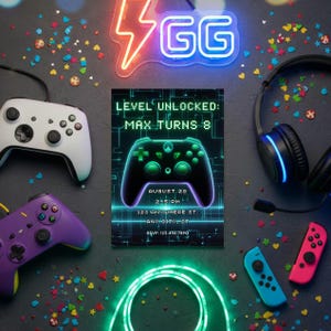 May include: A gaming-themed birthday invitation with a black background. The invitation reads "Level Unlocked: Max Turns 8" and includes date, time, and RSVP information. Game controllers, headphones, and neon lights surround the invitation.