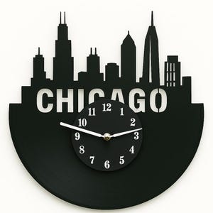 Könnte beinhalten: Schwarze Schallplattenuhr mit einer Silhouette der Skyline von Chicago mit dem Wort "CHICAGO" in weißen Buchstaben. Das Zifferblatt der Uhr ist schwarz mit weißen Zahlen und Zeigern.