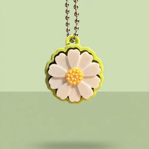 May include: A daisy-shaped pendant with white petals and a yellow centre, outlined in green. The pendant hangs from a silver ball chain, creating a cheerful and nature-inspired accessory.
