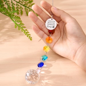 May include: A rainbow crystal suncatcher with a clear crystal ball at the bottom. The suncatcher has a series of colorful faceted beads and a circular charm with the text "LOOK FOR ME IN THE RAINBOWS Bingo".