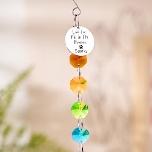 May include: A hanging rainbow crystal suncatcher with a silver charm that reads "Look For Me In The Rainbows" and "Sparky". The suncatcher has a series of colorful faceted crystals in orange, green, and blue.