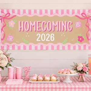 Peut inclure: Une bannière rectangulaire à rayures verticales roses et blanches, avec le texte HOMECOMING 2026 en rose et blanc. Le centre est beige avec des illustrations florales roses et des rubans, au-dessus d'une table avec des cupcakes et des fleurs.