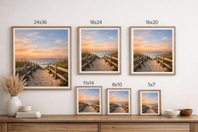 May include: Framed beach landscape art prints in various sizes, including 24x36 inches, 18x24 inches, 16x20 inches, 11x14 inches, 8x10 inches, and 5x7 inches. The prints depict a sandy path leading to the ocean at sunset, framed in light wood.
