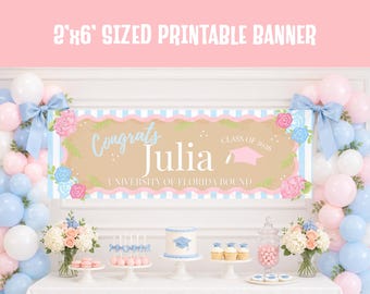 May include: A 2' x 6' printable banner with the text "Congrats Julia" and "Class of 2026". The banner has a light brown center with blue and pink floral accents and a light blue and white striped border. Balloons and a dessert table are in the background.