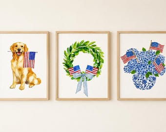 May include: Watercolour art prints in wooden frames. The set includes a golden retriever holding an American flag, a green wreath with flags and a blue bow, and a blue floral arrangement with flags.
