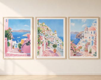 May include: Three framed watercolour prints showing coastal scenes with pink and white buildings, blue water, and lush greenery. The artwork evokes a Mediterranean village with vibrant colours and a sunny atmosphere.