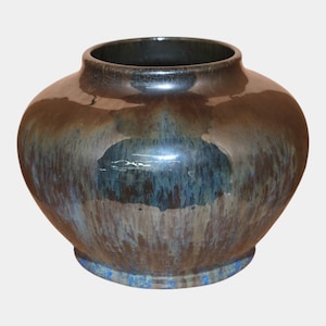 May include: A round, glazed ceramic vase with a wide body and a narrow opening. The vase has a dark brown and blue-green color scheme with a glossy finish. The base of the vase has a blue accent.
