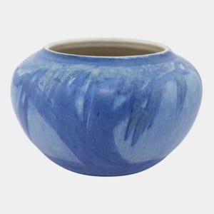 May include: A round, blue ceramic vase with a wide opening and a light interior. The exterior features a marbled effect with shades of blue. The vase has a smooth, glossy finish and is suitable for decorative purposes.