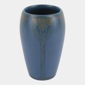 May include: A matte blue ceramic vase with a tapered cylindrical shape. The upper portion features a decorative pattern of muted green leaf-like shapes and small brown circular accents that extend downward in thin vertical lines along the body.