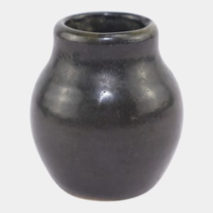 May include: A small, dark gray ceramic vase with a rounded body and a slightly flared rim. The vase has a smooth, glossy finish and a simple, elegant design. The vase is approximately 4 inches tall.
