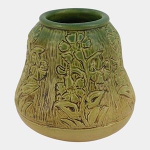 May include: A ceramic vase with a rounded shape and a wide opening. The exterior features a relief pattern of flowers and leaves in shades of olive green and tan. The surface has a textured finish with a darker green glaze around the rim.