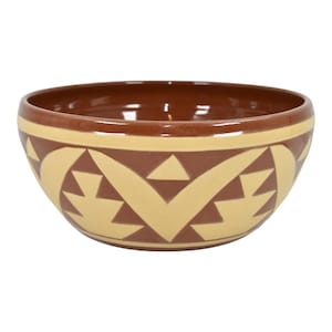 May include: A ceramic bowl with a brown interior and rim, featuring a cream-colored geometric pattern against a brown background. The bowl has a rounded shape and is likely used for serving food.