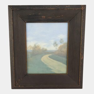 May include: Framed landscape art print featuring a winding road through a green field under a cloudy sky. The artwork is enclosed in a dark brown wooden frame with decorative detailing on the edges.