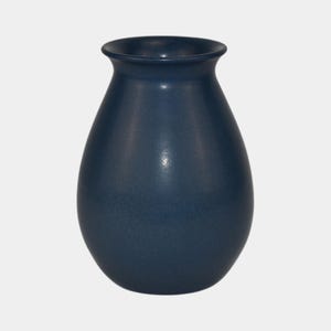 May include: A navy blue ceramic vase with a rounded body and a slightly flared rim. The vase has a smooth, matte finish and a classic, timeless design. It is a decorative item suitable for displaying flowers or as a standalone accent piece.