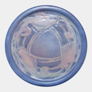 May include: A round, blue ceramic bowl with a raised floral design in the center. The bowl has a light blue and pink color scheme with a darker blue rim. The floral design is a lighter shade of pink and blue.