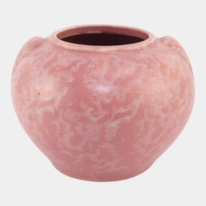 May include: A round, pink ceramic vase with a textured surface and two small handles. The vase has a wide opening and a slightly darker interior. The overall shape is bulbous, with a smooth, matte finish.