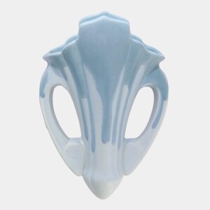 May include: A light blue and white ceramic vase with a unique, stylized design. The vase features a central, fluted body with two curved handles and a flared top. The color gradient adds depth to the decorative piece.