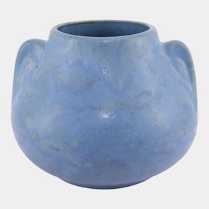 May include: A blue ceramic vase with two curved handles. The vase has a rounded body and a wide opening. The surface has a mottled appearance with lighter blue and gray tones.