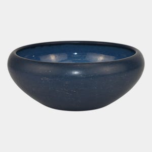 May include: A navy blue ceramic bowl with a rounded shape and a dark blue interior. The bowl has a smooth, matte finish and is suitable for serving food or as a decorative piece. The bowl's dimensions are not visible.