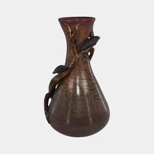 May include: A decorative vase with a brown and bronze finish, featuring a tree branch design with black leaves and birds. The vase has a textured surface and a flared top.