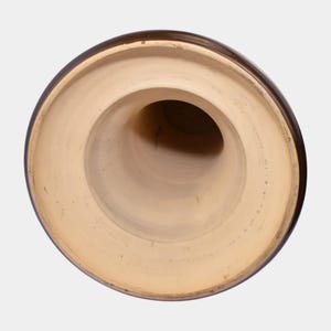 May include: A brown ceramic vase viewed from the inside, showcasing a wide, circular rim and a tapered, cylindrical interior. The interior is a light beige color, contrasting with the dark brown exterior.