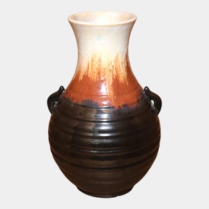 May include: A ceramic vase with a wide, rounded base and a slender neck. The top is cream-colored, transitioning to a burnt orange and then a dark brown base. It has two small, curved handles and a glossy finish.