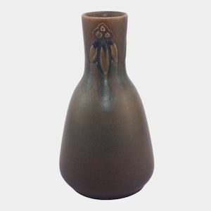 May include: A brown ceramic vase with a rounded body and a narrow neck. The vase features a decorative embossed floral design on the neck. The color gradient transitions from a dark brown at the base to a lighter brown at the top, with hints of green and blue.