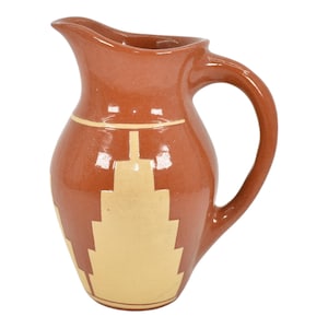 May include: A terracotta pitcher with a geometric design in a light yellow color. The pitcher has a wide mouth and a handle.