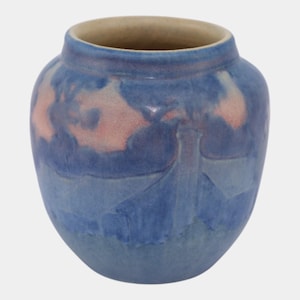 May include: A blue ceramic vase with a wide, rounded body and a slightly flared rim. The vase features a mottled design with shades of blue and hints of pink. The interior is a light beige color. A decorative piece for the home.