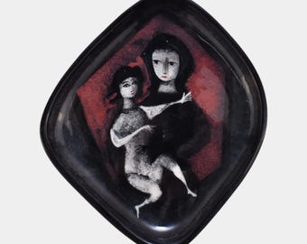 May include: A black, diamond-shaped ceramic dish with a stylized painting of two figures. The figures are depicted in white and black against a red background. The dish has a glossy finish.
