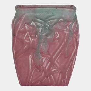 May include: A square-shaped ceramic vase with a textured surface. The vase is primarily a dusty rose color, with a gradient of pale green at the top. The design features raised, abstract floral patterns.