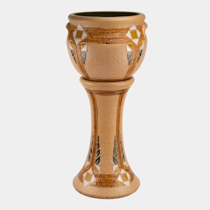 May include: A beige ceramic plant stand with a decorative design. The stand features a round top and base, connected by a slender, fluted column. Geometric patterns in yellow, white, and blue adorn the stand's surface, adding visual interest to this decorative piece.