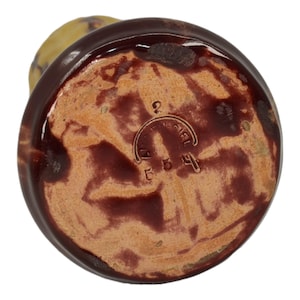 May include: Bottom view of a brown and tan ceramic vase. The base is a reddish-brown color with a lighter tan center. The base has a circular stamp with the text "LE CIEL" and the numbers "554".