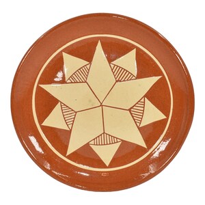 May include: A terracotta plate with a white eight-pointed star design in the center.