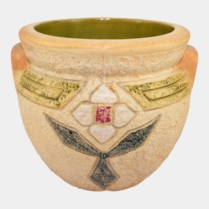 May include: A beige ceramic pot with a textured surface and a floral design. The pot features a white flower with a red center, green and black leaves, and two small handles. The interior is green.