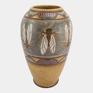 May include: A ceramic vase featuring a central band of gray glaze decorated with repeating brown and white insect motifs. The upper and lower sections are finished in a tan glaze, with decorative geometric borders in green and purple tones.